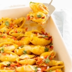 Taco stuffed shells in a white baking pan.
