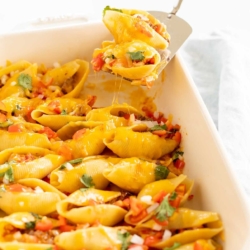 Taco stuffed shells in a white baking pan.