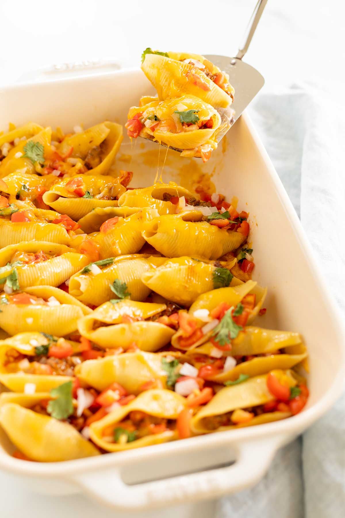 Taco stuffed shells in a white baking pan.