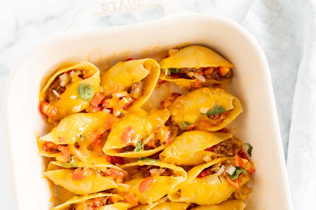 Taco stuffed shells in a white baking pan.
