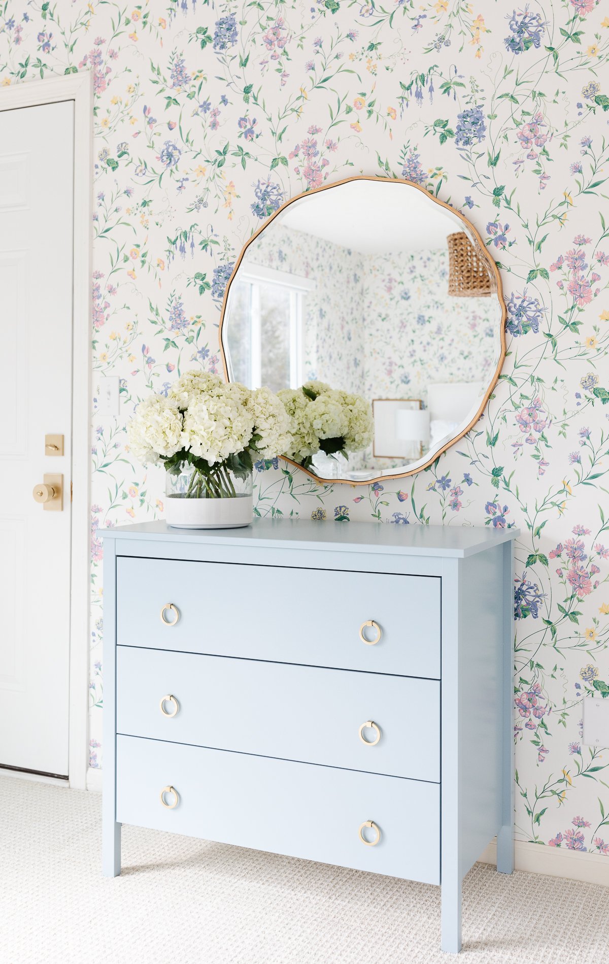 blue chest of drawers with gold mirror and floral wallpaper