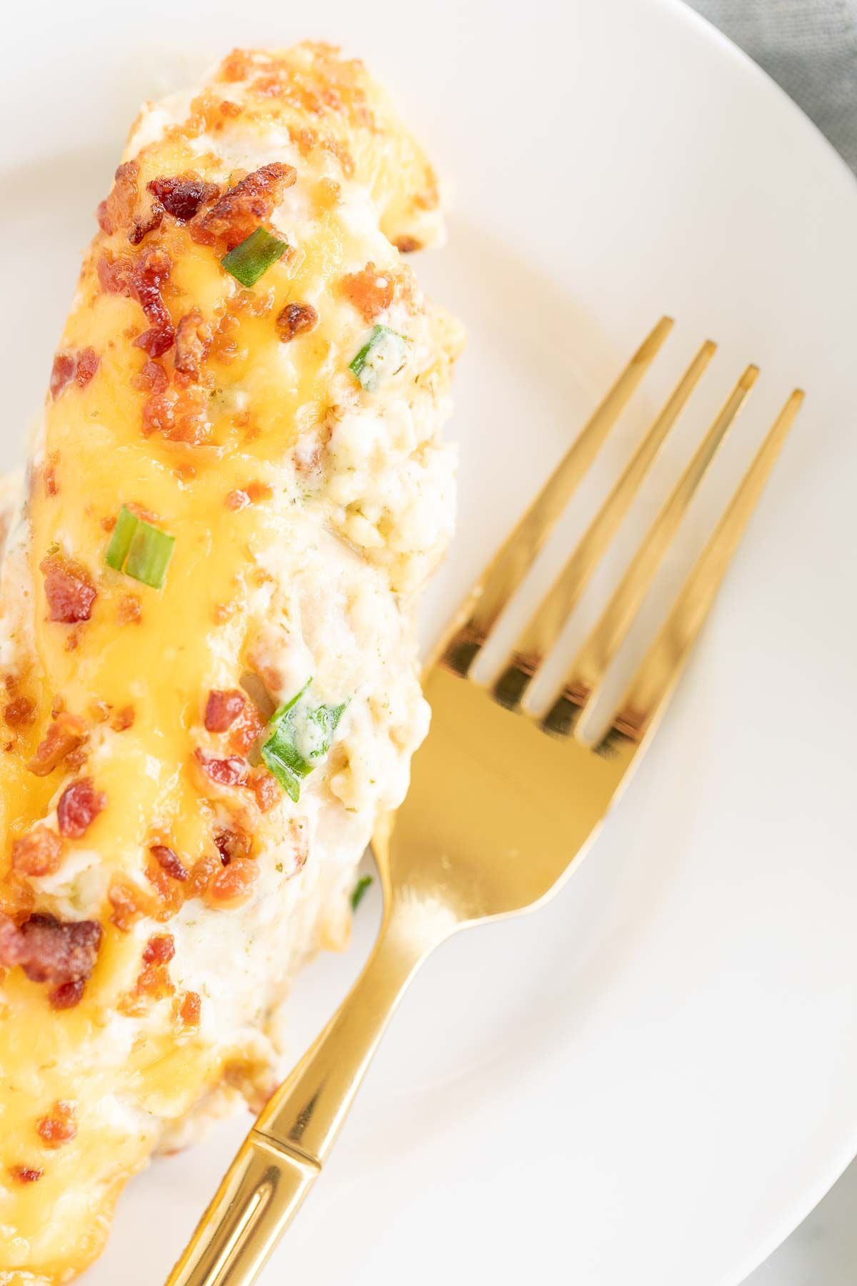 A crack chicken tenderloin serving on a white plate with a gold fork.