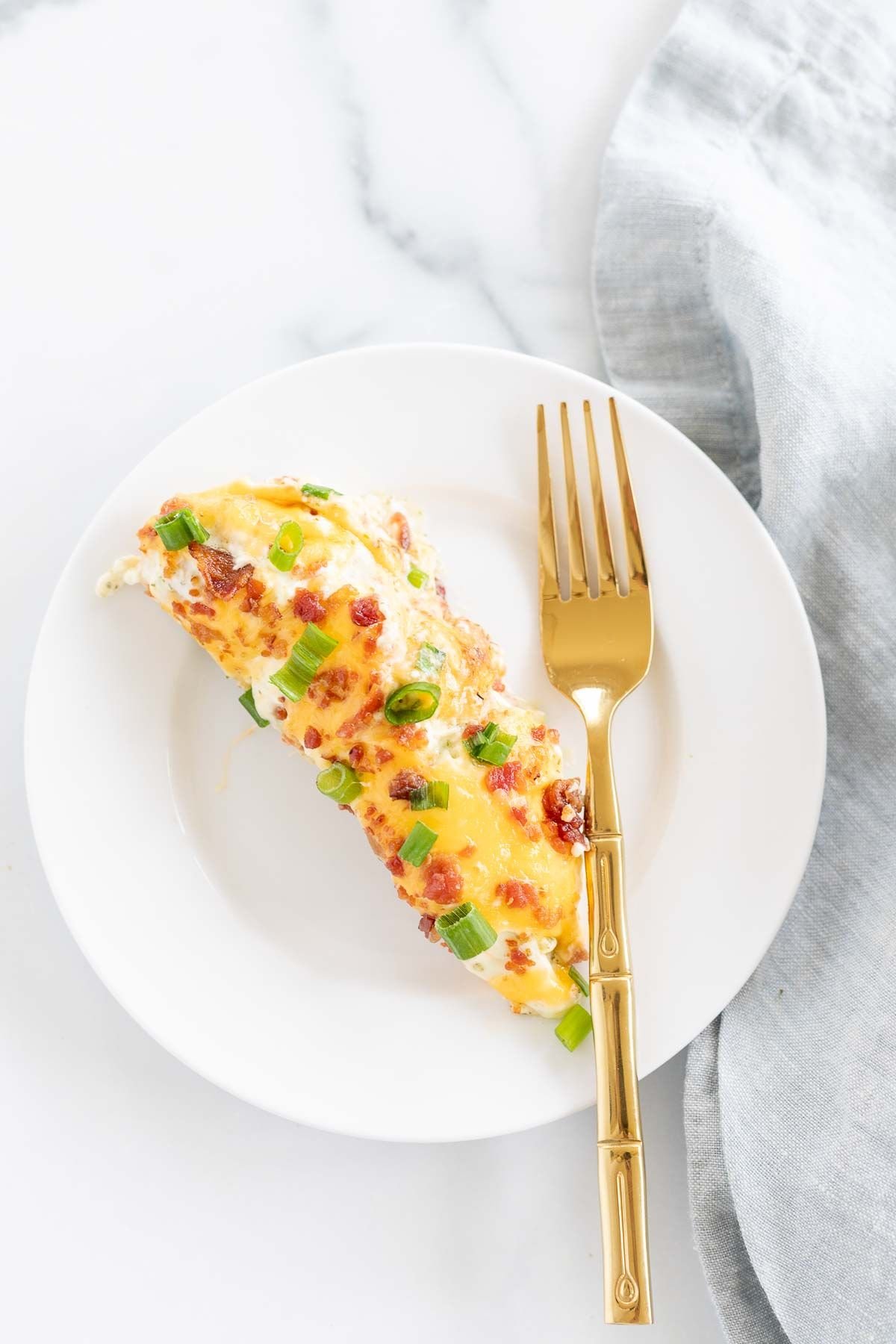 A crack chicken tenderloin serving on a white plate with a gold fork.