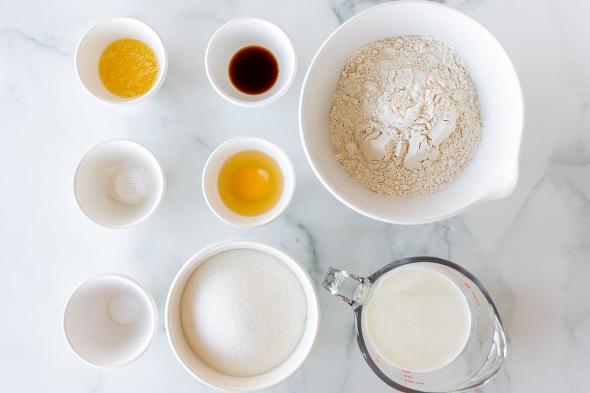 Ingredients for homemade Christmas donuts laid out on a marble surface.
