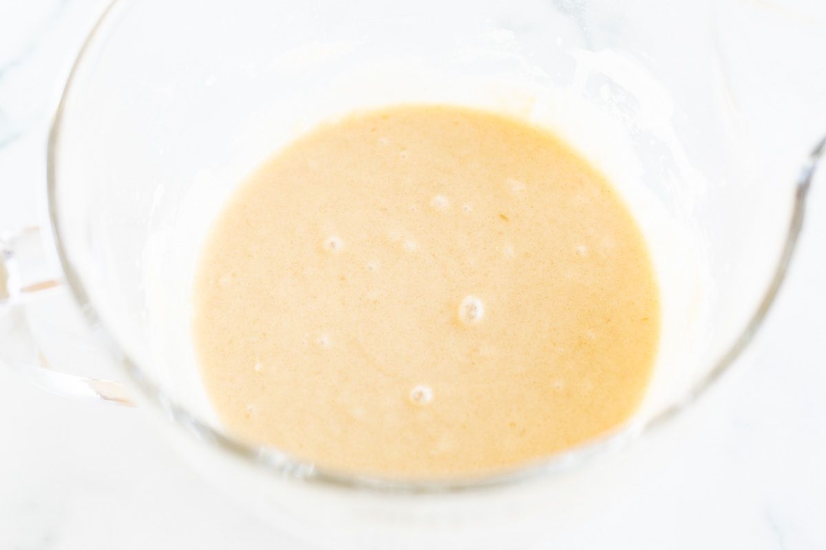 A clear mixing bowl with batter for homemade Christmas donuts.