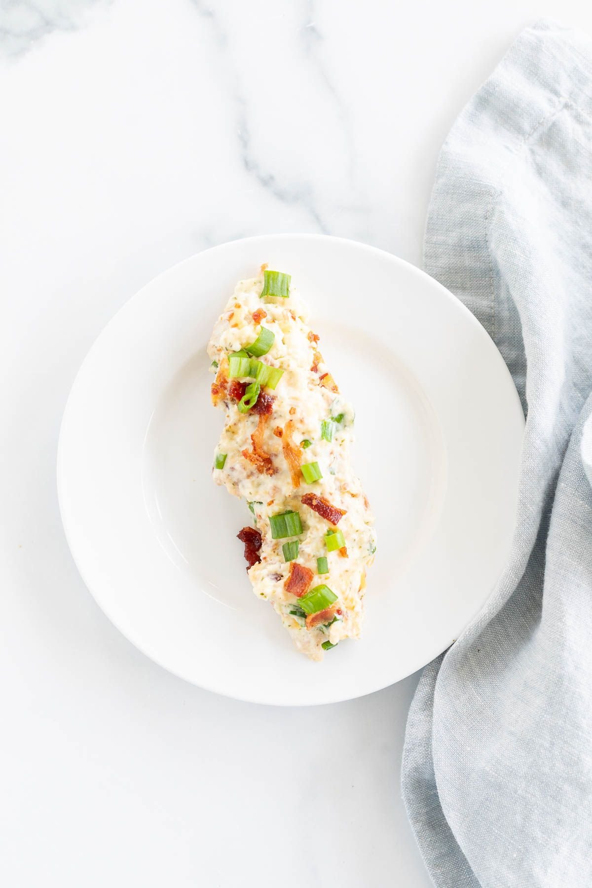 A crack chicken tenderloin serving on a white plate with a gold fork.