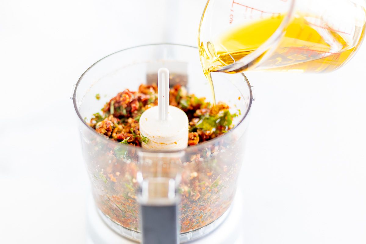 A food processor filled with ingredients for sun dried tomato pesto