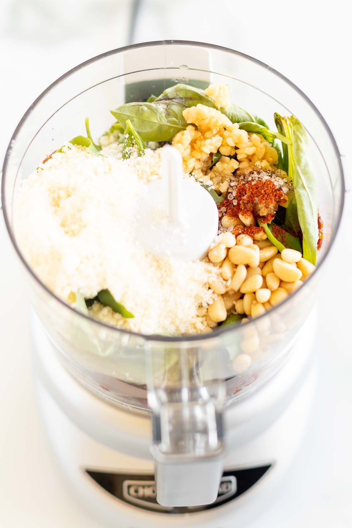 A food processor filled with ingredients for sun dried tomato pesto