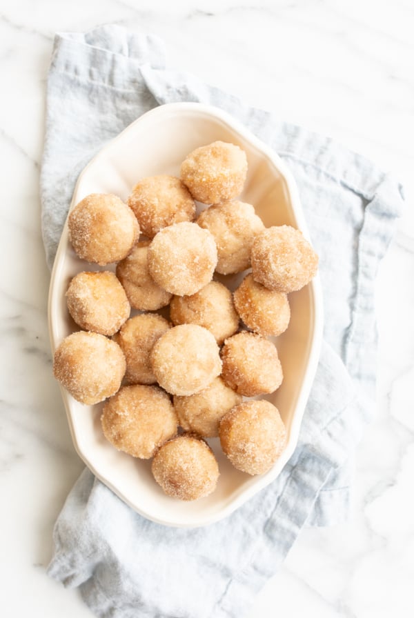 A white oval platter full of mini cinnamon muffins.