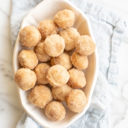 A white oval platter full of mini cinnamon muffins.