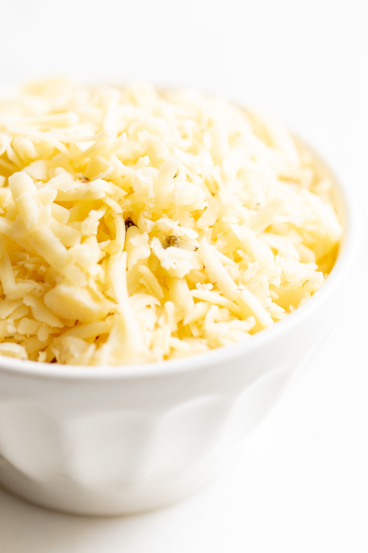 A white bowl full of shredded cheese