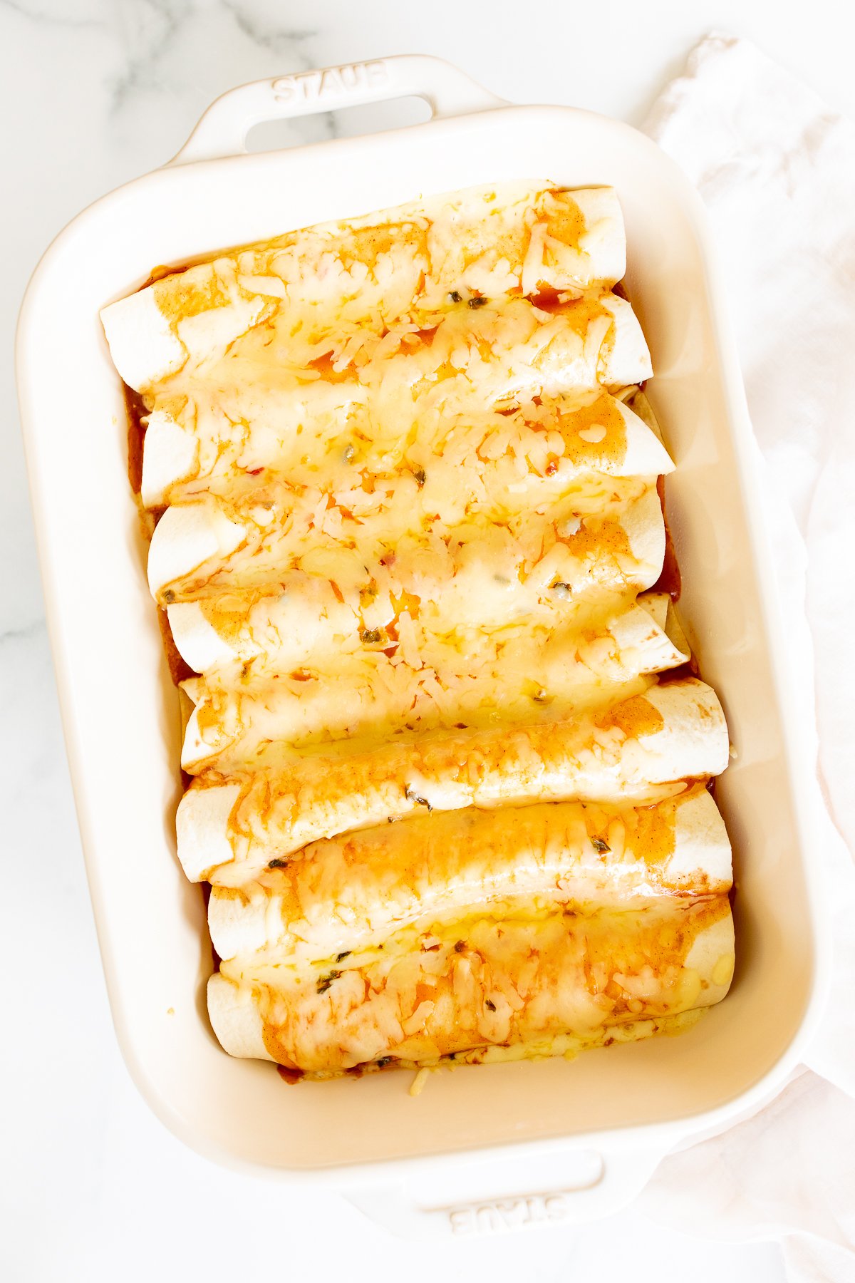 Cheese enchiladas in a white baking dish.