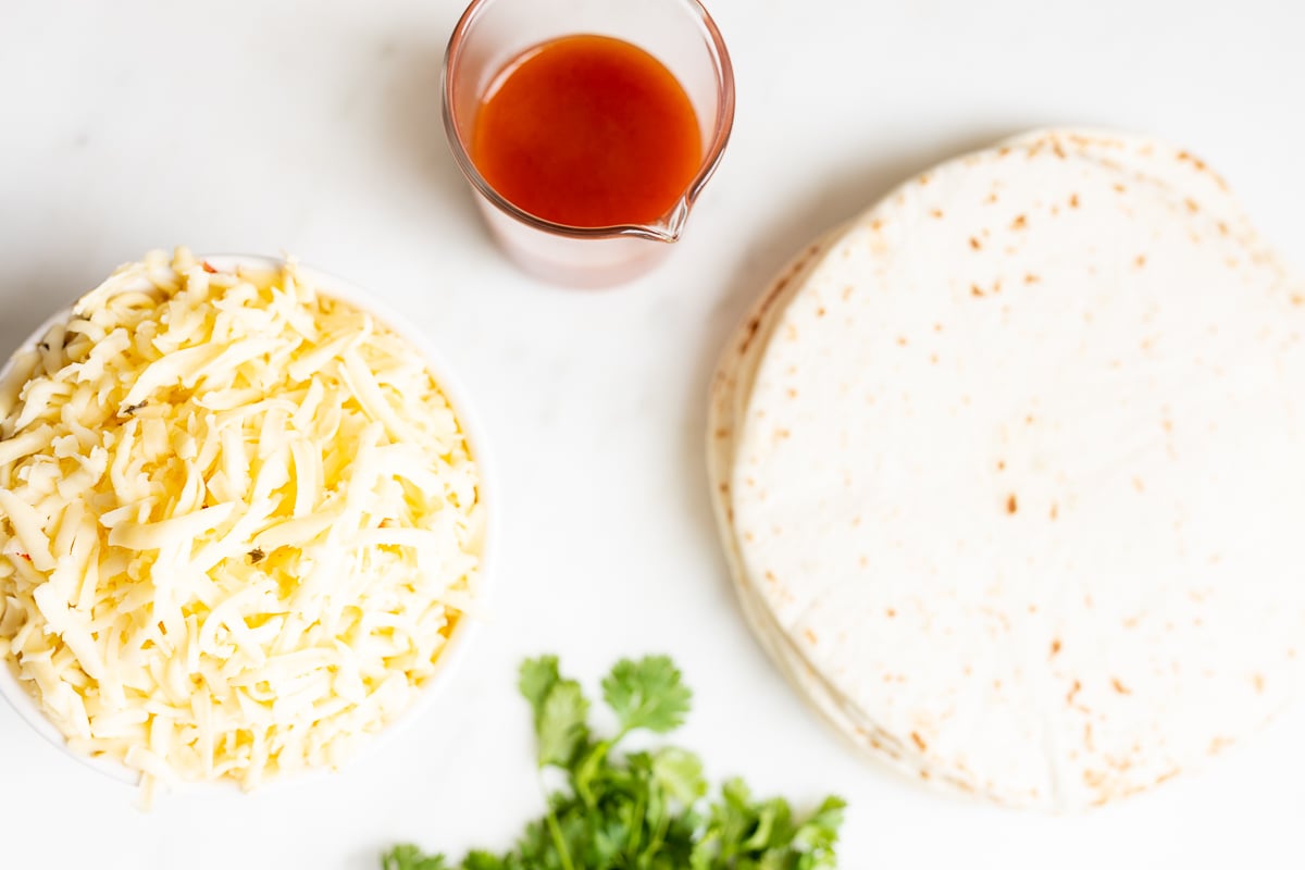 ingredients for cheese enchiladas on a white countertop