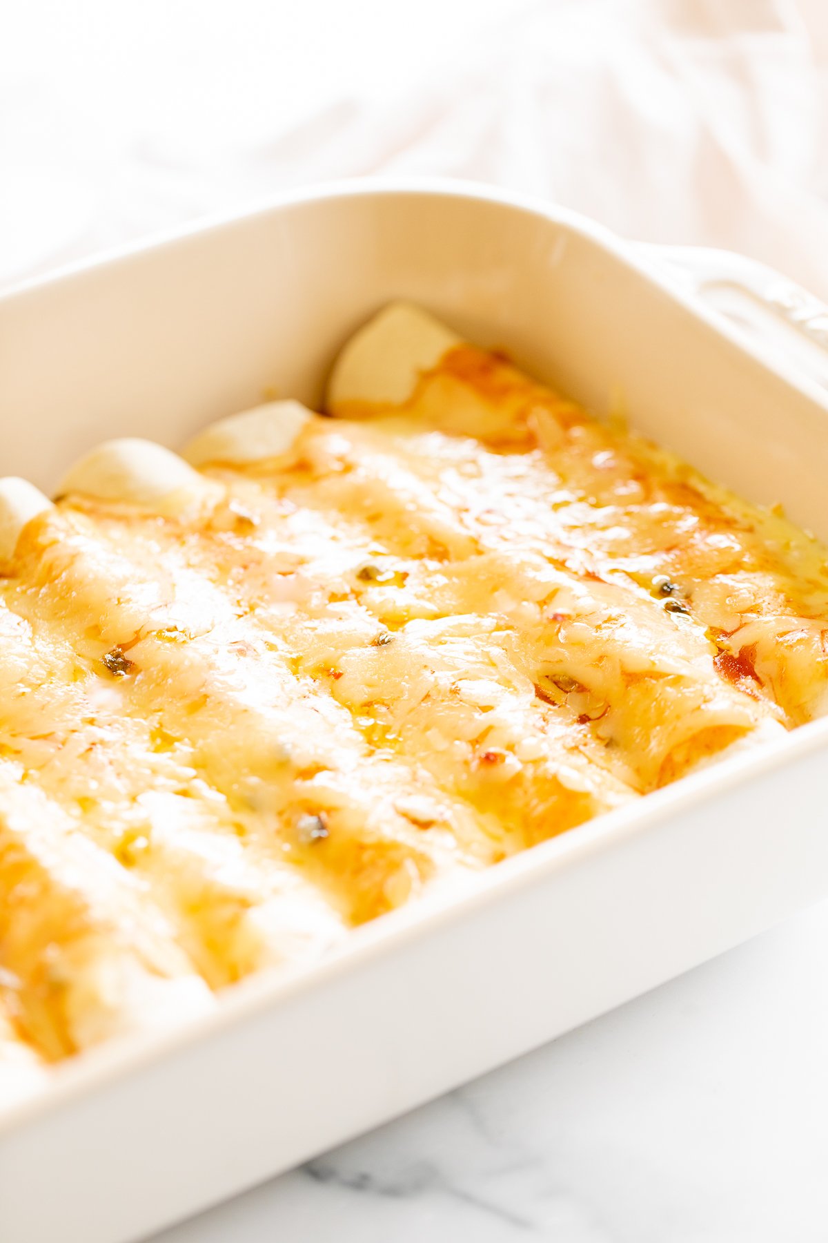 Cheese enchiladas in a white baking dish.