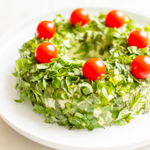 A basil pesto wreath make ahead christmas appetizer on a white plate