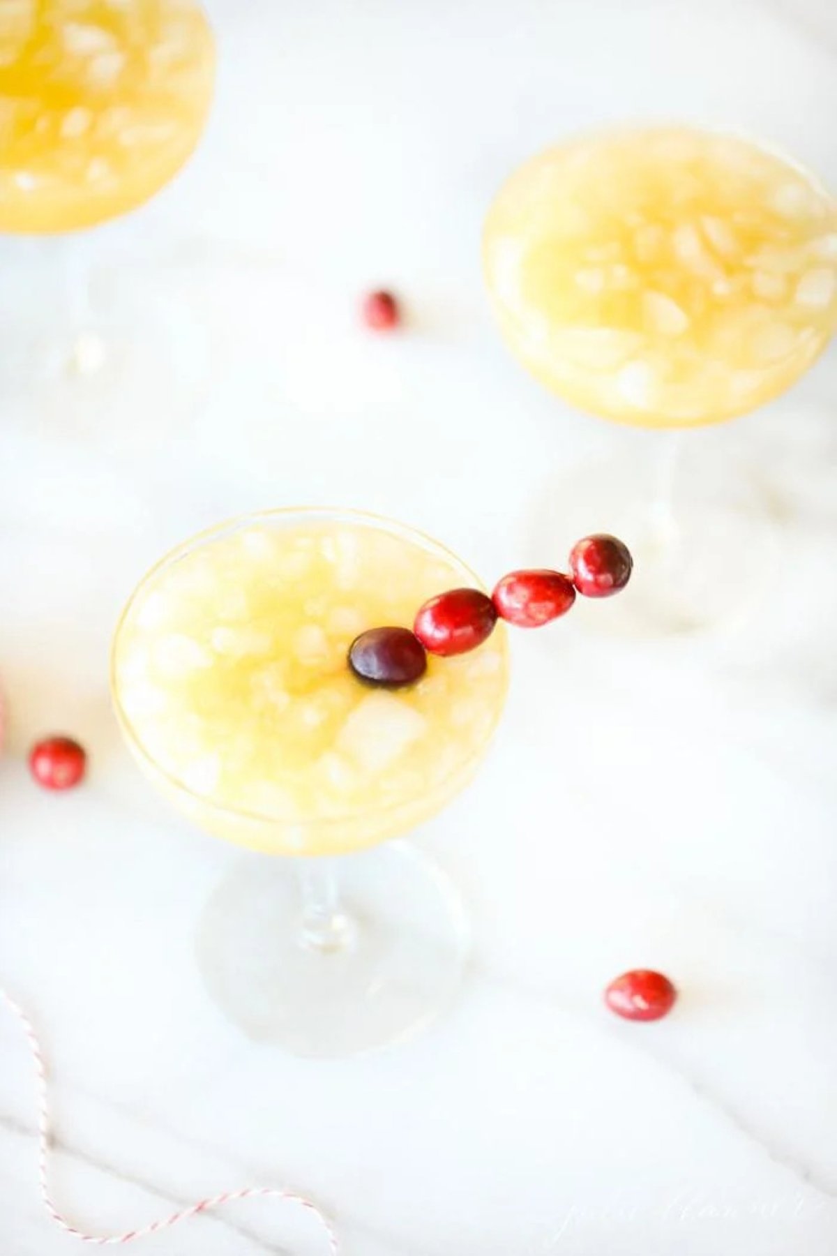 mai tai with cranberry skewer in a clear glass stemmed vase.