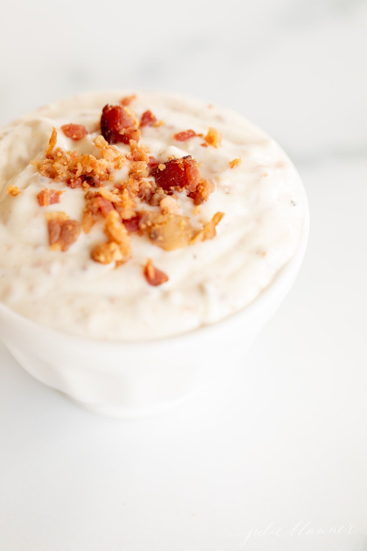 Bacon aioli in a small white bowl on a marble surface.