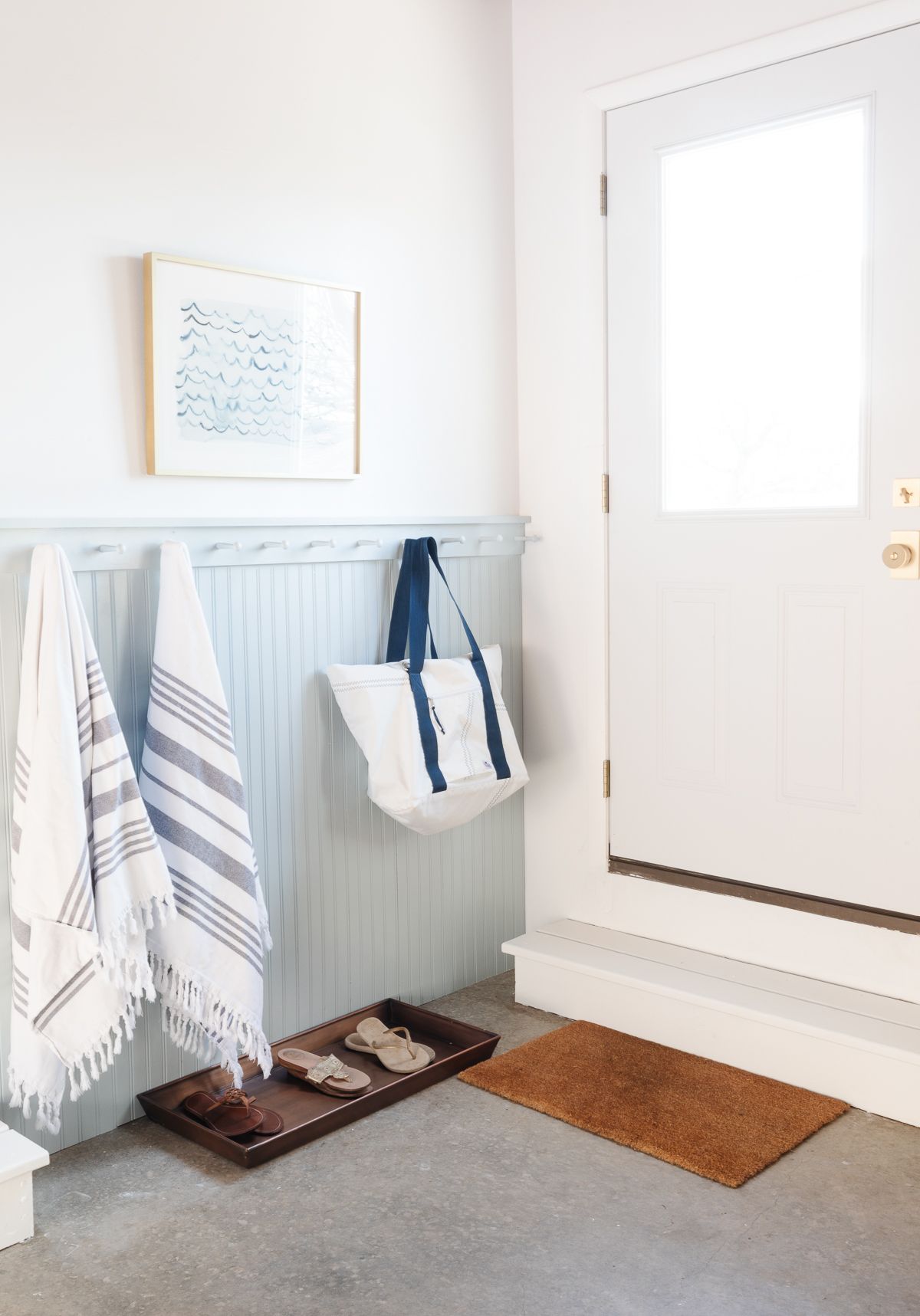 A blue painted mudroom area with a boot tray on the ground.