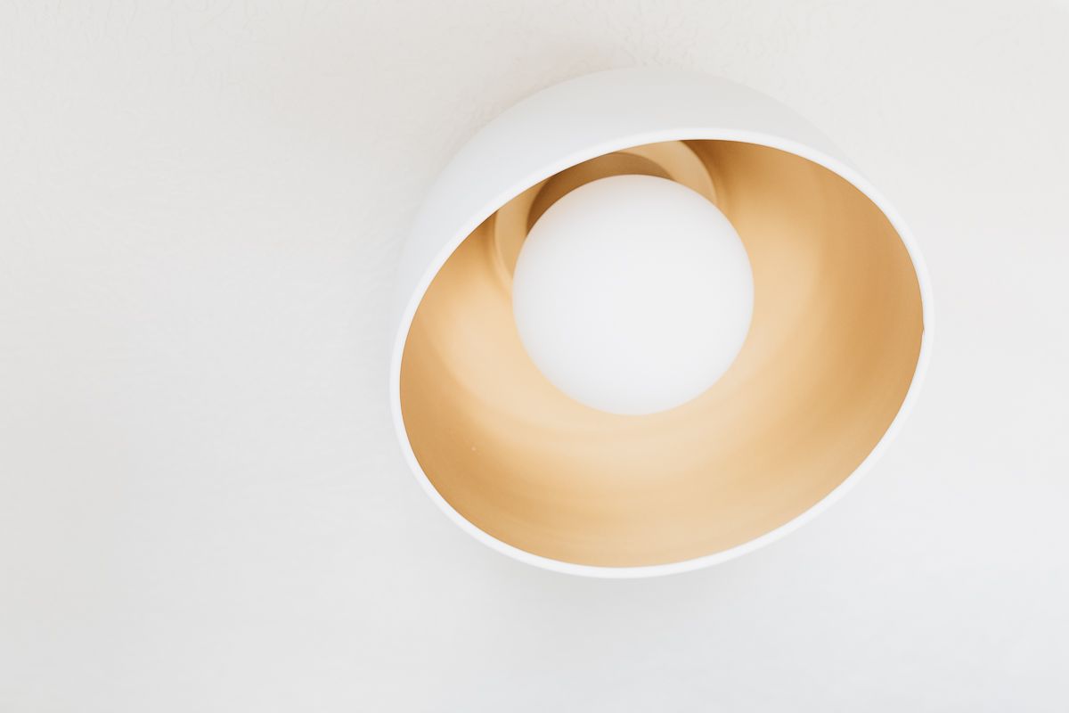 A modern gold flush mount light fixture on a white ceiling.