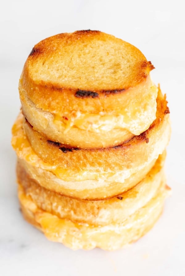 A stack of 3 pimento grilled cheese sandwiches on a marble countertop.