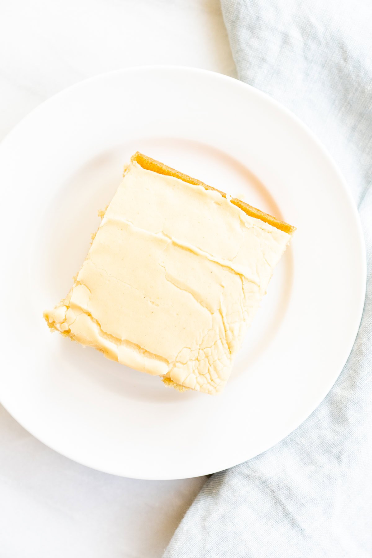 A slice of frosted peanut butter cake on a white plate against a bright white background.