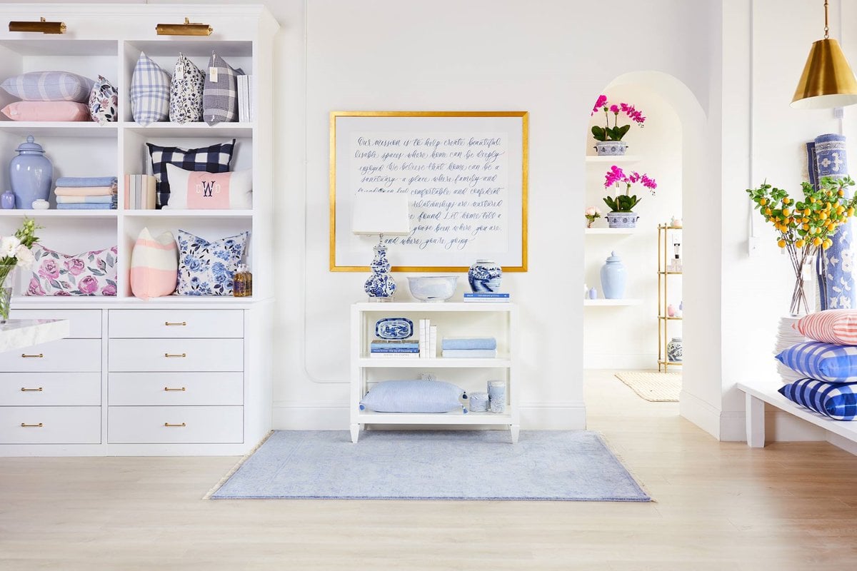 Caitlin Wilson retail store, featuring product displays and a shelving unit with brass picture lights. 