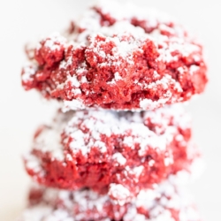 A stack of red velvet gooey butter cookies on a white surface.