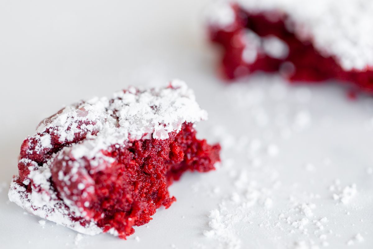 Red velvet gooey butter cookies dusted in powder sugar on a white countertop.