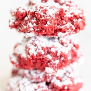 A stack of red velvet gooey butter cookies on a white surface.