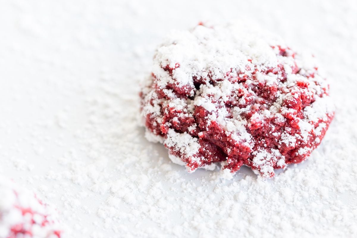 Red velvet gooey butter cookies dusted in powder sugar on a white countertop.