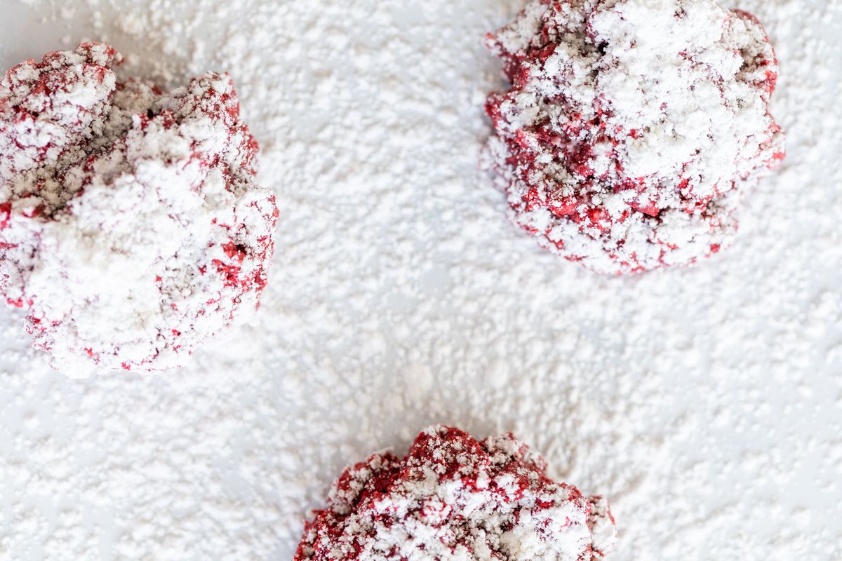 Red velvet gooey butter cookies dusted in powder sugar on a white countertop.