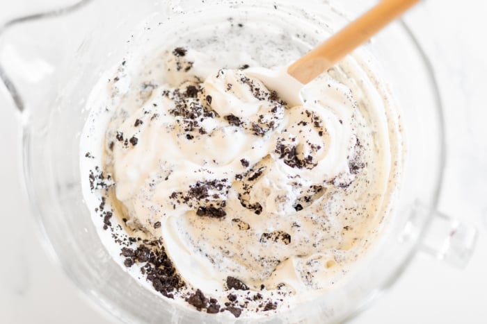 Rubber spatula folding Oreo bits into no-churn cookies and cream ice cream