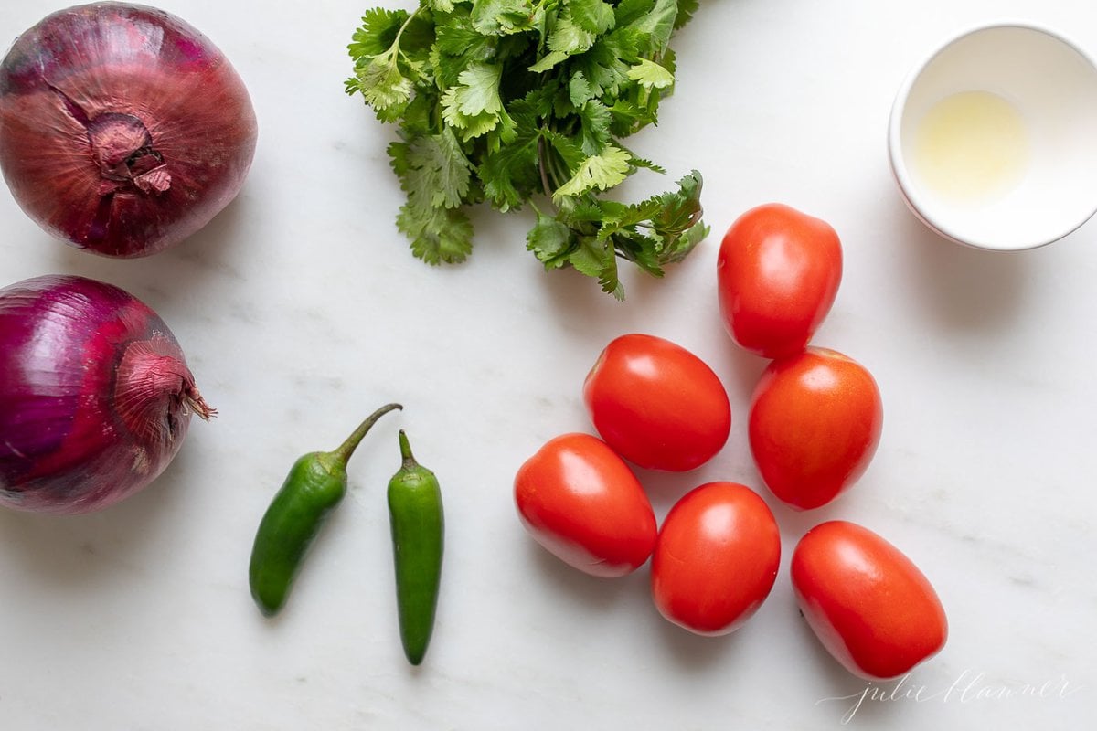 Ingredients for guacamole laid out on a white countertop.