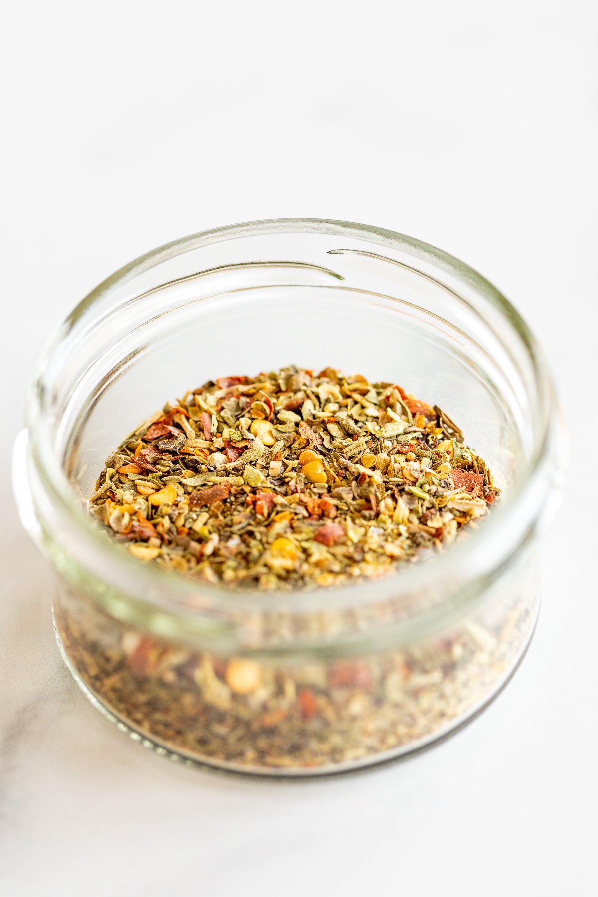 Jar of oregano seasoning on marble countertop