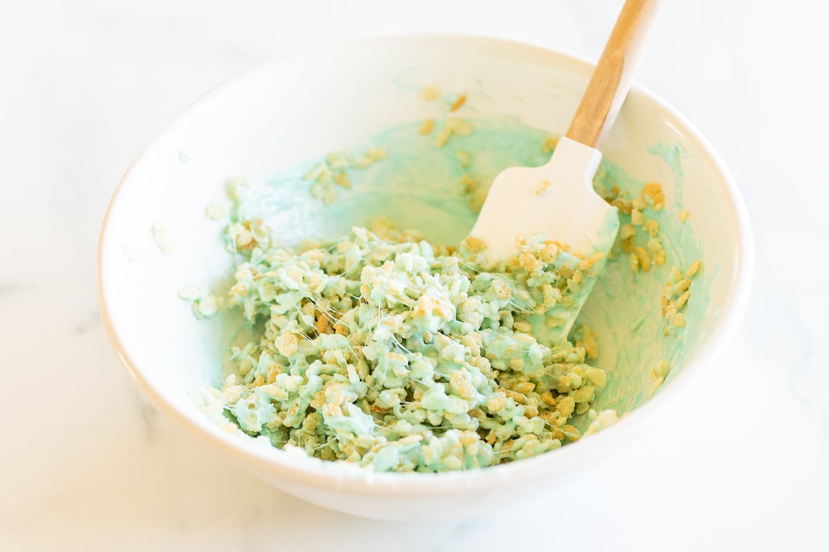 Spatula stirring Rice Krispies into blue marshmallow mixture for Peeps treats