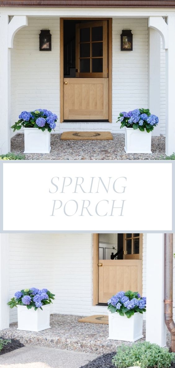 A white brick house with a wooden Dutch door and white planters on the spring porch, filled with blue hydrangeas.