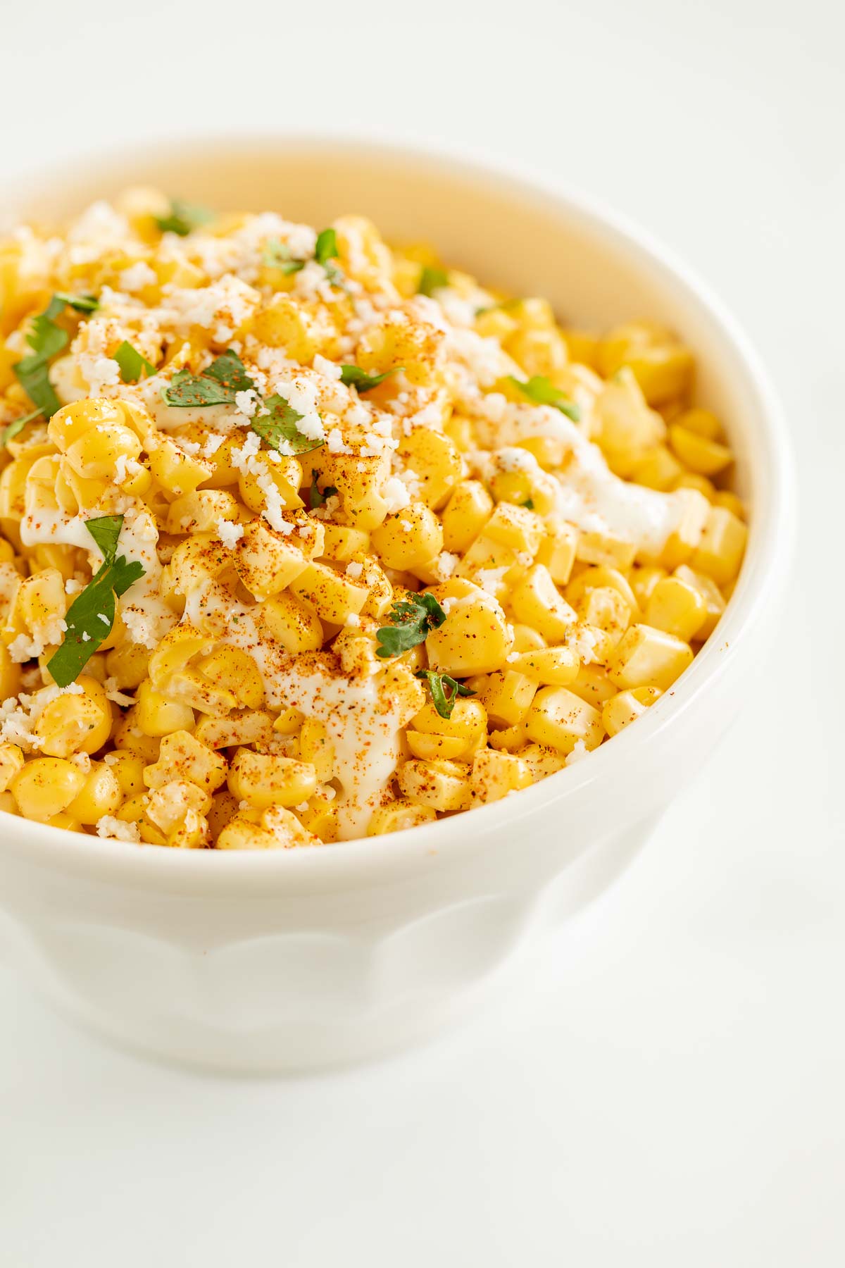 A white bowl of esquites (Mexican street corn salad).