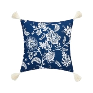 An outdoor blue and white floral pillow with tassels.