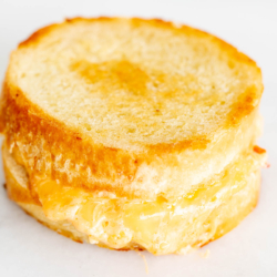 A pimento grilled cheese sandwich on round bread, on a marble countertop.