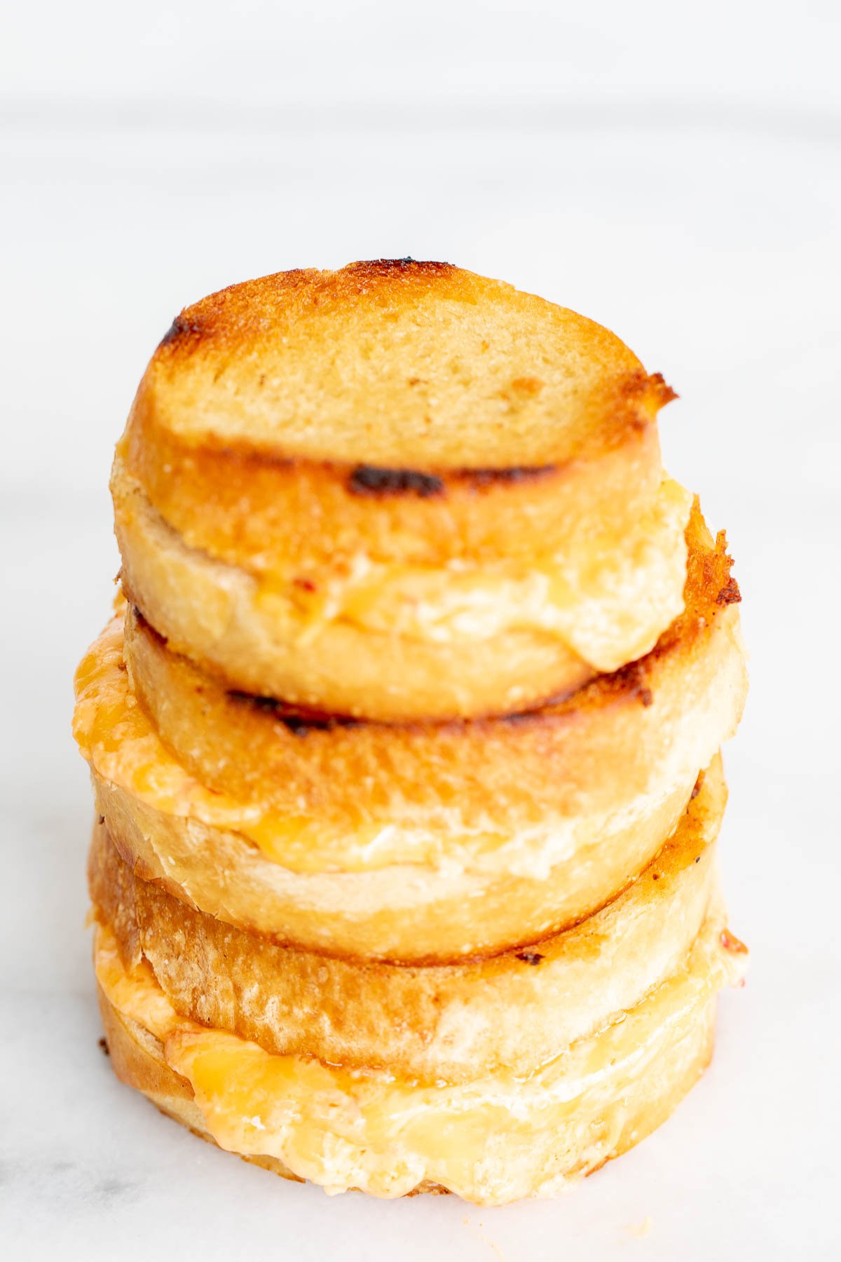 A stack of 3 pimento grilled cheese sandwiches on a marble countertop. 