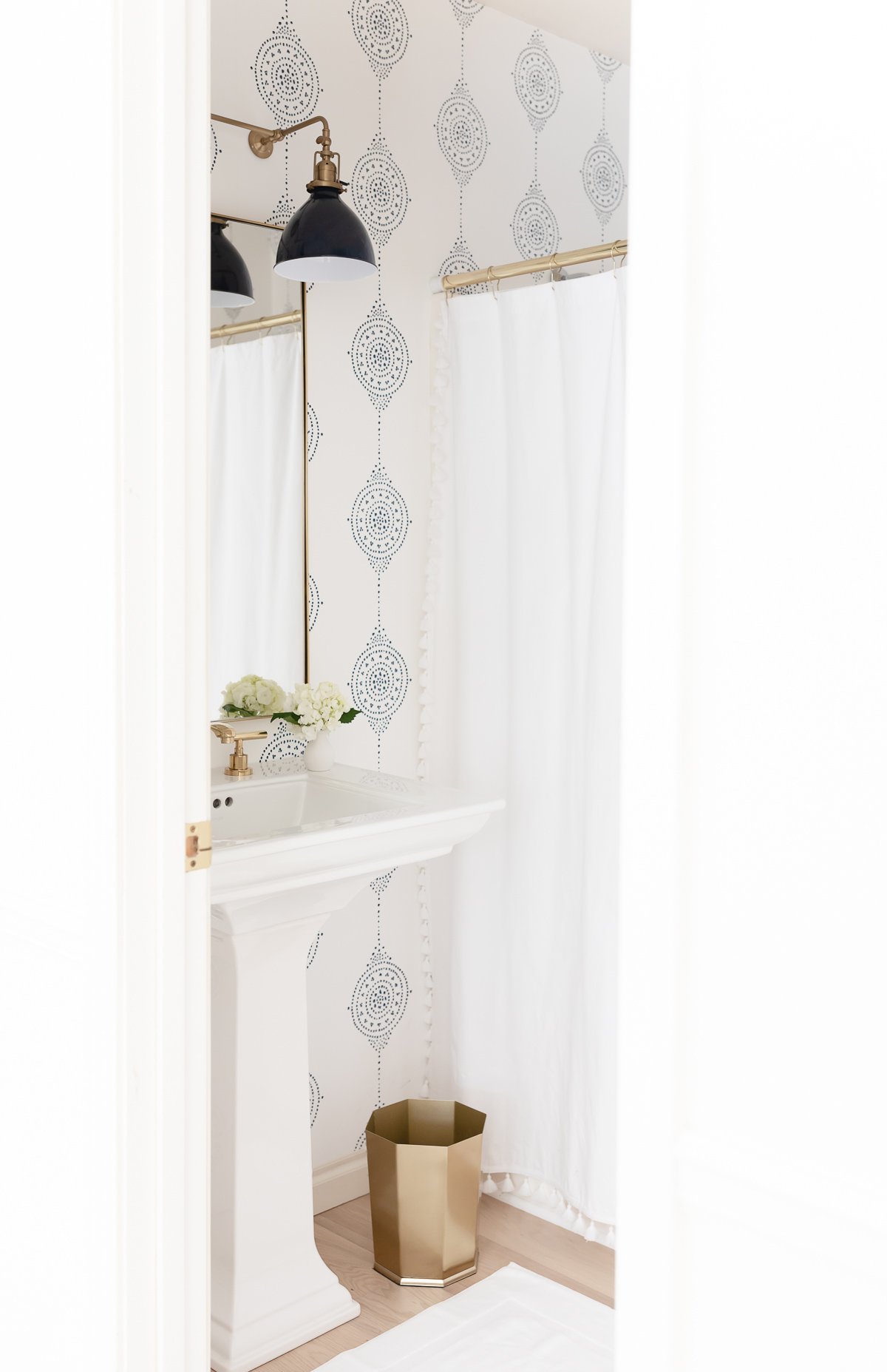 bathroom with pedestal sink, navy light and wallpaper