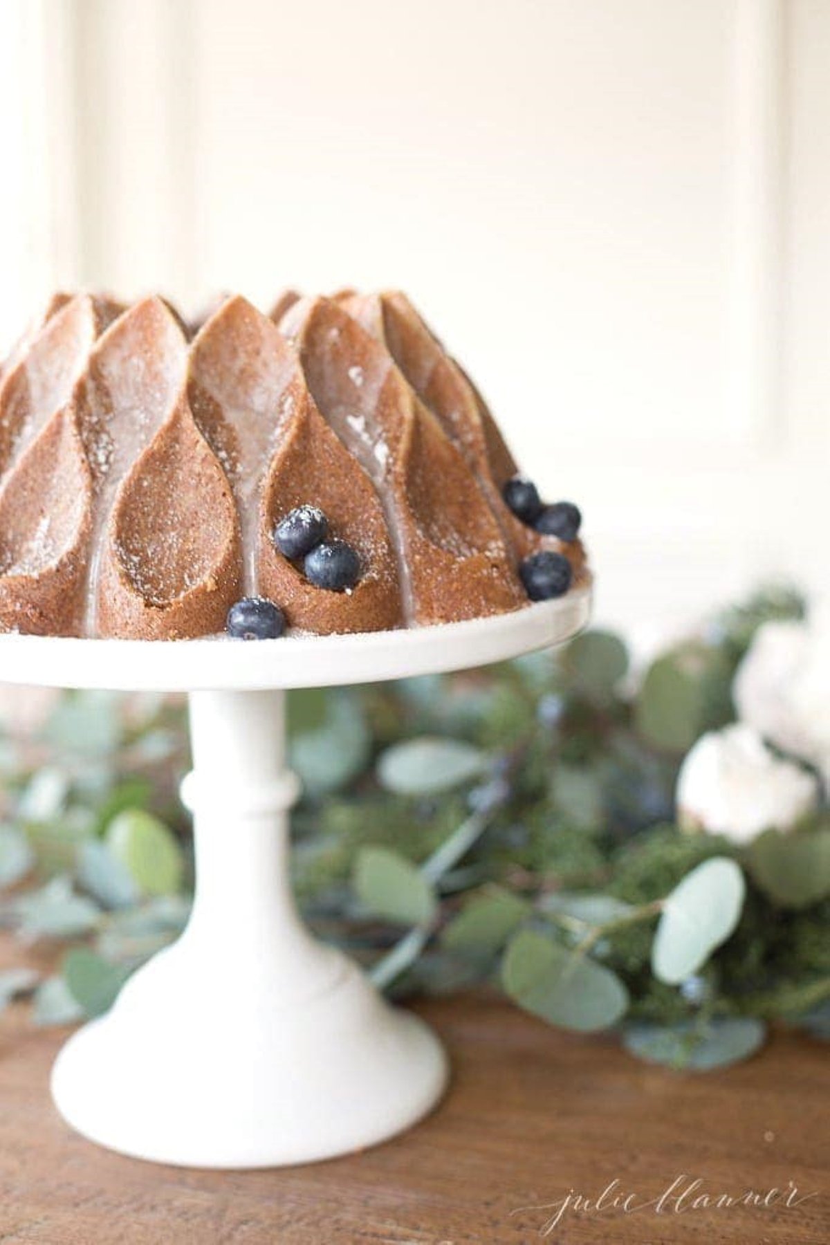 a cinnamon pound cake on a white cake pedestal.