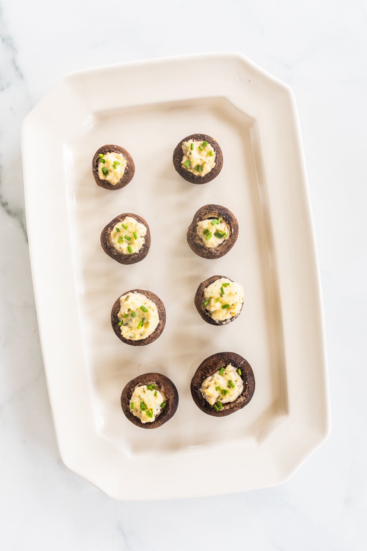 A white platter serving Boursin stuffed mushrooms. 