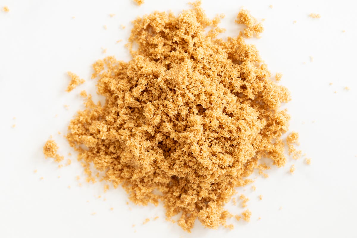 Dark brown sugar scattered on a white surface.