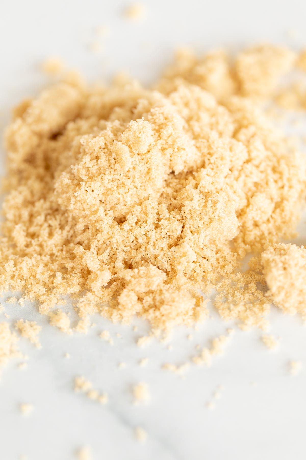 Light brown sugar piled on a white surface.