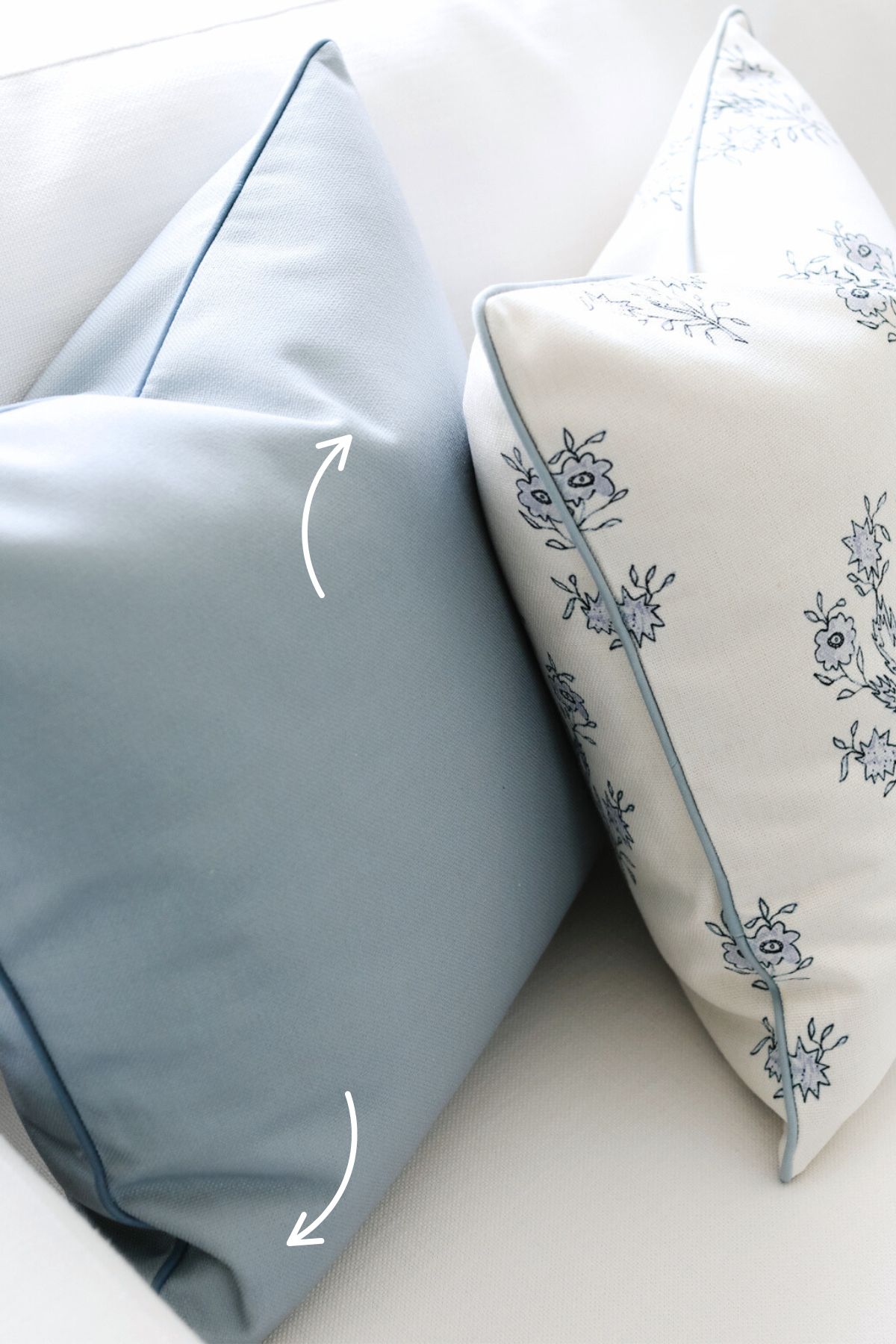 Two pillows on a white sofa, one solid light blue and the other white with blue floral patterns and piping. Pillow inserts ensure they maintain perfect form, while arrows indicate they are placed at an angle.