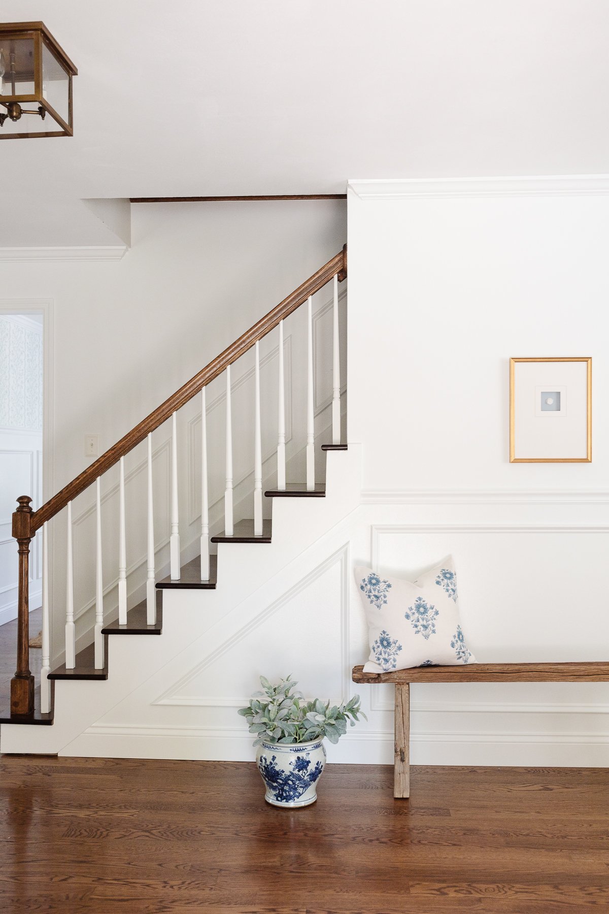 An entryway staircase with molding painted in Sherwin Williams Extra White.