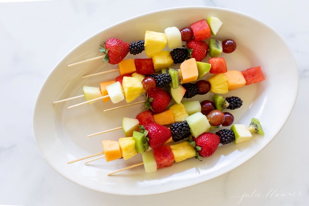 fruit skewers on a white platter