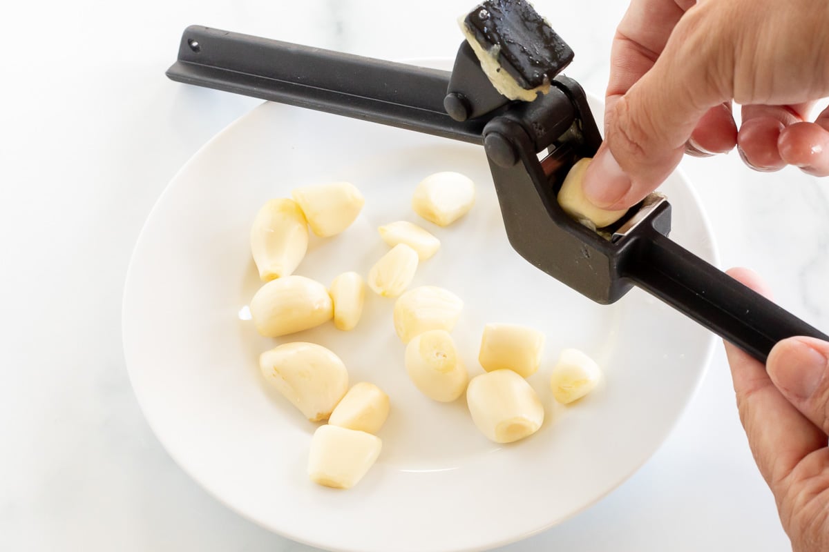 Hand placing garlic gloves into garlic press