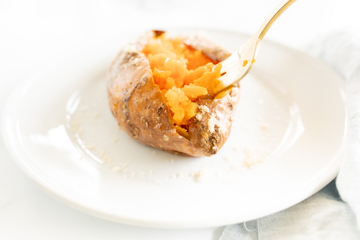 A grilled sweet potato on a white plate.